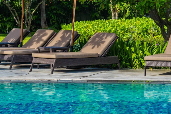 Bellissimo ombrellone e sedia intorno alla piscina all'aperto in caldo — Foto Stock