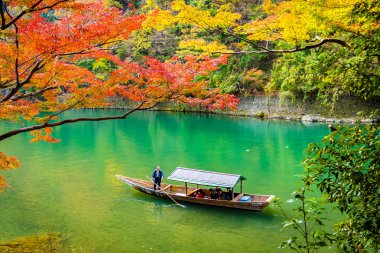Akçaağaç ağaç yaprak ve etrafında tekne ile güzel Arashiyama Nehri 