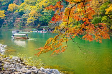 Akçaağaç ağaç yaprak ve etrafında tekne ile güzel Arashiyama Nehri 