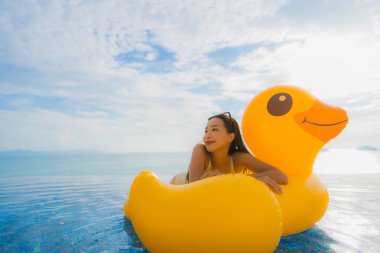 Portrait young asian woman on inflatable float yellow duck aroun clipart