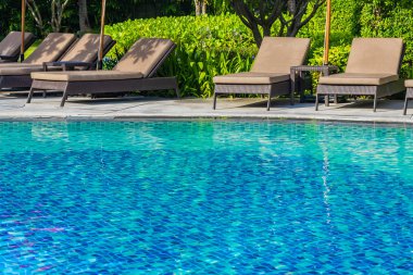 Sıcak açık yüzme havuzu etrafında güzel şemsiye ve sandalye