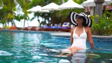 Güzel Asyalı bir kadının oteldeki havuzda dinlenirken çekilmiş görüntüleri.
