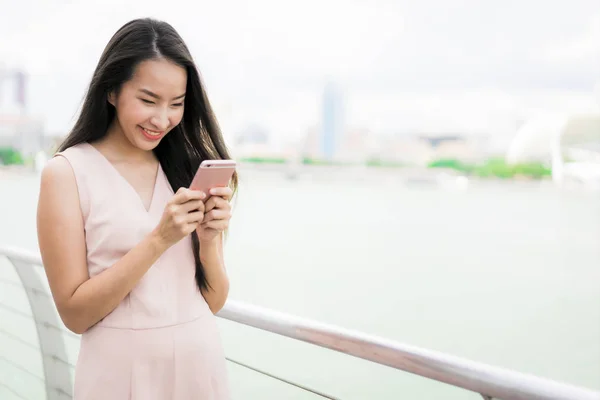 Азиатка, использующая смартфон или мобильный телефон для разговоров или смс — стоковое фото