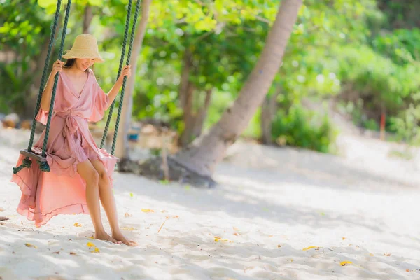 Retrato joven asiática mujer sentado en swing cuerda y mar alrededor — Foto de Stock