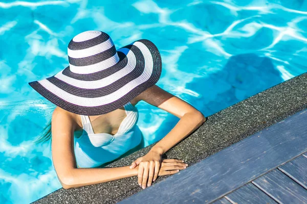 Bonita jovem mulher asiática com chapéu na piscina para viagens — Fotografia de Stock