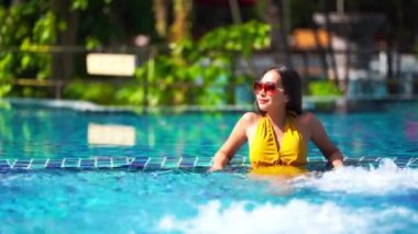 Güzel Asyalı bir kadının oteldeki havuzda dinlenirken çekilmiş görüntüleri.