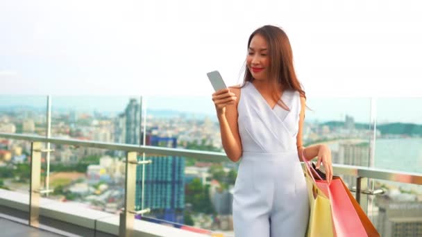 Πλάνα Από Όμορφη Ασιάτισσα Γυναίκα Χρησιμοποιώντας Smartphone Χάρτινες Σακούλες Μπροστά — Αρχείο Βίντεο