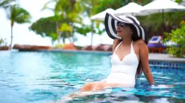 Güzel Asyalı bir kadının oteldeki havuzda dinlenirken çekilmiş görüntüleri.