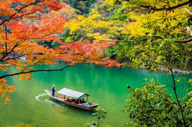 Akçaağaç ağaç yaprak ve etrafında tekne ile güzel Arashiyama Nehri 