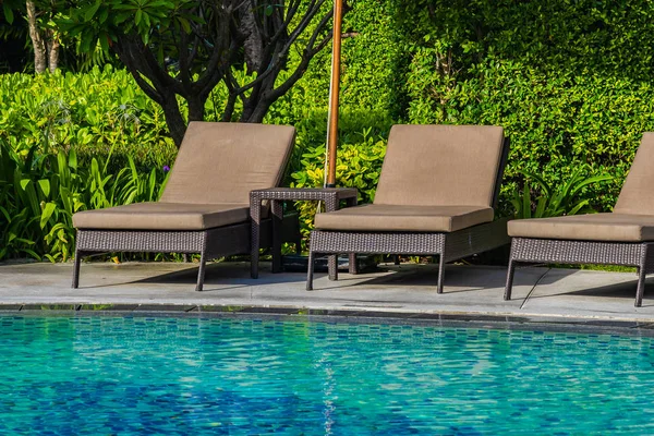 美丽的雨伞和椅子周围的室外游泳池在热 — 图库照片