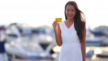 Yatların önünde duran altın kartlı güzel Asyalı kadının görüntüleri.