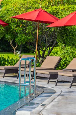 Sıcak açık yüzme havuzu etrafında güzel şemsiye ve sandalye