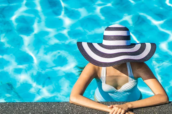 Bonita jovem mulher asiática com chapéu na piscina para viagens — Fotografia de Stock