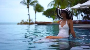 Güzel Asyalı bir kadının oteldeki havuzda dinlenirken çekilmiş görüntüleri.