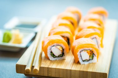 Somon Balık et suşi roll maki ahşap plaka üzerinde