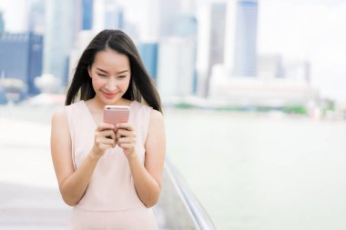 Asyalı kadın konuşmak veya metin için akıllı telefon veya cep telefonu kullanarak