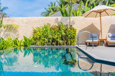 Şemsiye ve boş tatil ve tatil için mavi gökyüzü ve beyaz bulut ile deniz okyanusu plaj yakın yüzme havuzu etrafında sandalye