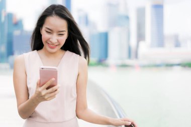 Asyalı kadın konuşmak veya metin için akıllı telefon veya cep telefonu kullanarak