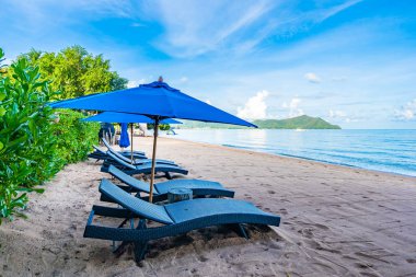 Tropikal plajda güzel şemsiye ve boş yatak sandalyesi ve