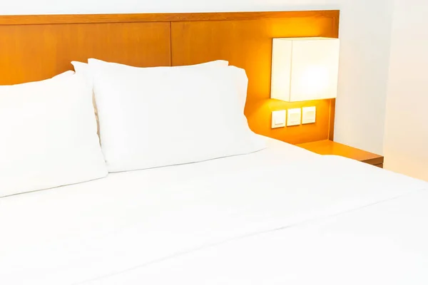 Fehér kényelmes párna ágyon könnyű lámpával díszítéssel a — Stock Fotó