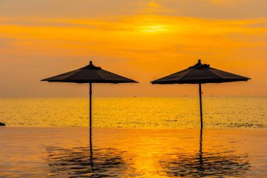 Şemsiye ve sandalye yüzme havuzu yakınında deniz okyanus plaj