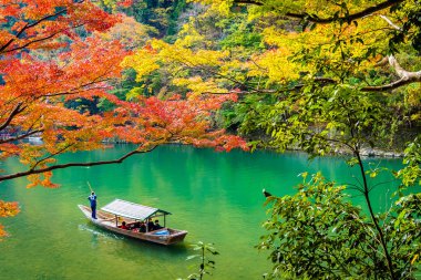 Akçaağaç ağaç yaprak ve etrafında tekne ile güzel Arashiyama Nehri 