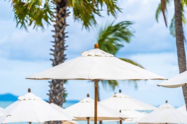 Deniz okyanusu plaj ve hindistan cevizi palmiye ağacı etrafında beyaz şemsiye