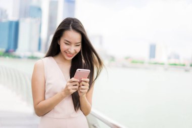 Asyalı kadın konuşmak veya metin için akıllı telefon veya cep telefonu kullanarak