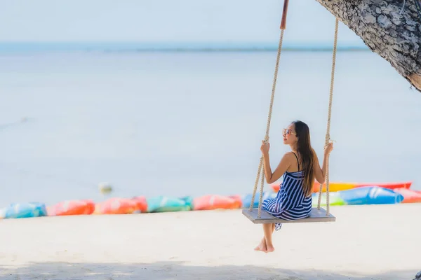 Портрет молодой азиатской женщины, сидящей на качелях и море вокруг — стоковое фото