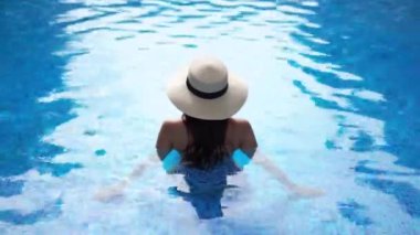 Güzel Asyalı bir kadının oteldeki havuzda dinlenirken çekilmiş görüntüleri.