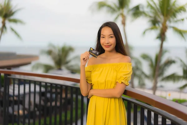 Krásné asijské ženy vykazují kreditní kartu s výhledem na mořské moře — Stock fotografie