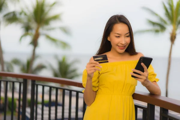 Hermosas mujeres asiáticas muestran tarjeta de crédito con vista al mar océano — Foto de Stock