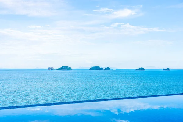 Beautiful outdoor swimming pool with sea ocean on white cloud bl — Stock Photo, Image