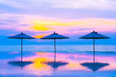 Şemsiye ve sandalye yüzme havuzu yakınında deniz okyanus plaj