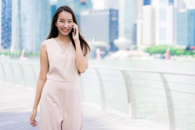 Asyalı kadın konuşmak veya metin için akıllı telefon veya cep telefonu kullanarak