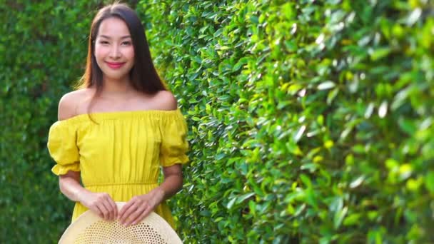 Metraje Hermosa Mujer Asiática Vestido Amarillo Frente Arbusto Verde — Vídeo de stock