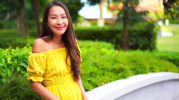 Кадры Красивой Азиатской Женщины Желтом Платье Перед Зеленым Кустом — стоковое видео