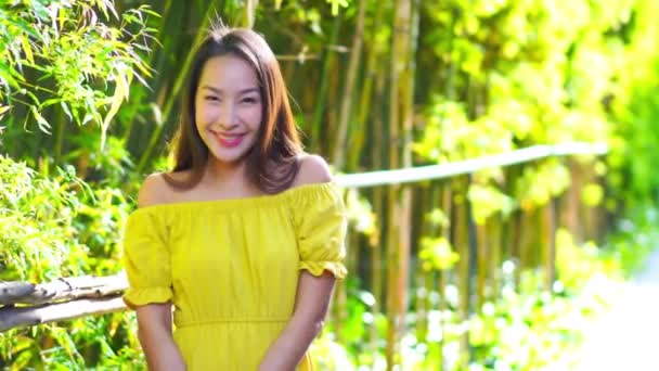 Záběry Krásné Asijské Ženy Žlutých Šatech Před Zeleným Keřem — Stock video