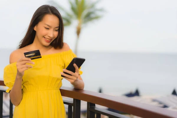 beautiful asian women show credit card with sea ocean view