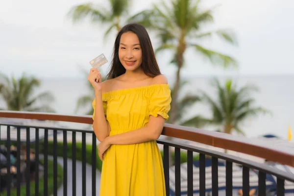 Krásné asijské ženy vykazují kreditní kartu s výhledem na mořské moře — Stock fotografie
