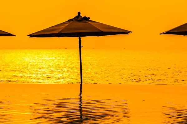 Parasol i krzesło wokół basenu neary morze oceanu plaży w — Zdjęcie stockowe