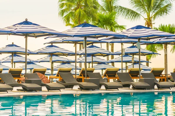 Otel re açık yüzme havuzu etrafında Şemsiye ve sandalye kanepe — Stok fotoğraf