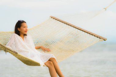Portre güzel genç Asyalı kadın etrafında hamak üzerinde oturuyor s