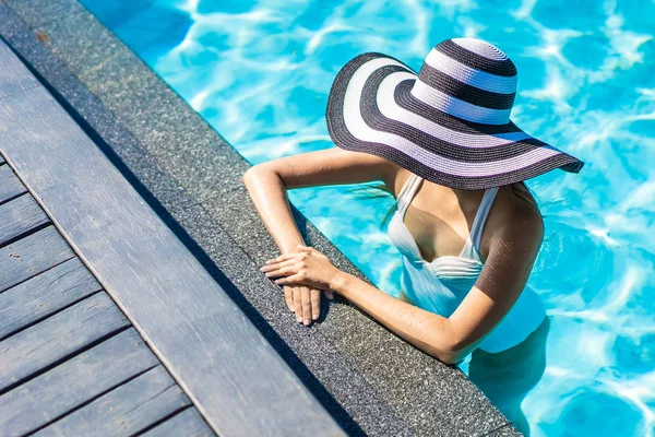 Bonita jovem mulher asiática com chapéu na piscina para viagens — Fotografia de Stock