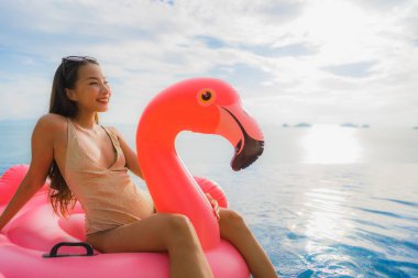 Portrait young asian woman on inflatable float flamingo around o clipart