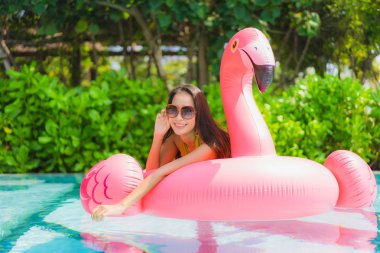 Portrait beautiful young asian woman on the flamingo inflatable  clipart