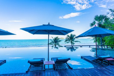 Şemsiye ve güzel lüks açık yüzme havuzu etrafında sandalye