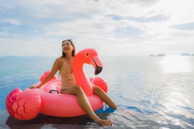 Portrait young asian woman on inflatable float flamingo around o clipart
