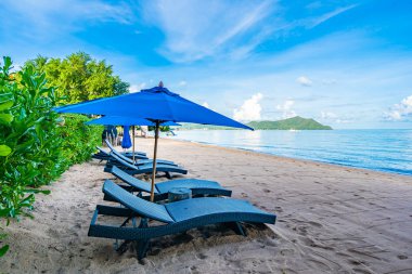 Tropikal plajda güzel şemsiye ve boş yatak sandalyesi ve