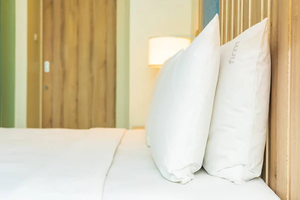 Travesseiro confortável branco na decoração da cama com lâmpada de luz — Fotografia de Stock